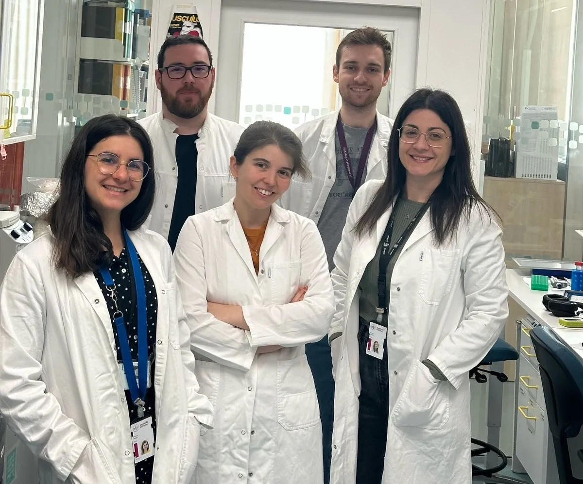 Group picture of five people in white lab coats in a lab environment.