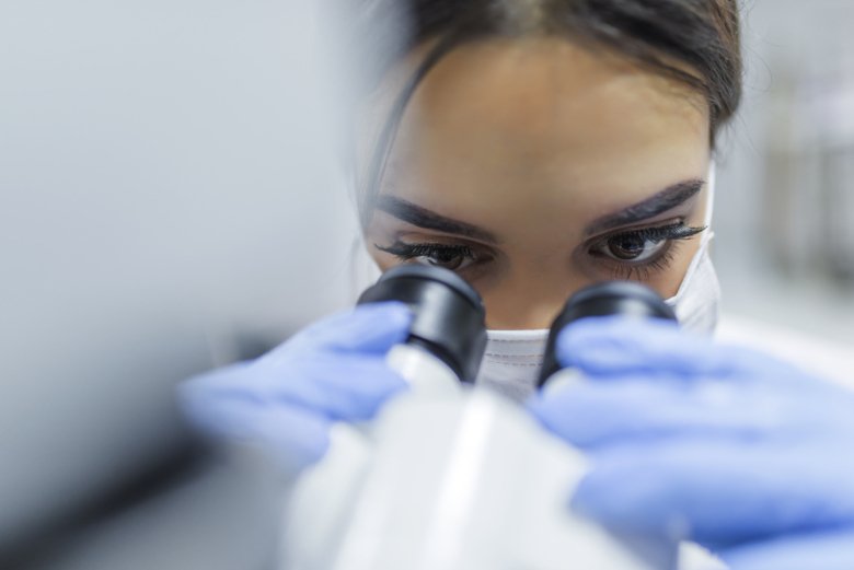 Female researcher with microscope.