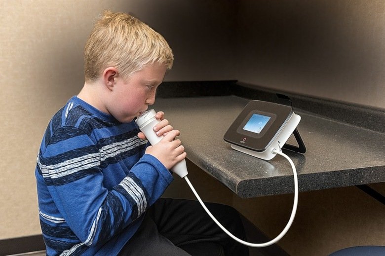Bild på en pojke som gör kvävemonoxidtestet för astmatiker.