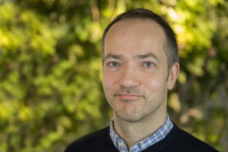 Close up photo of a man infront of some leaves