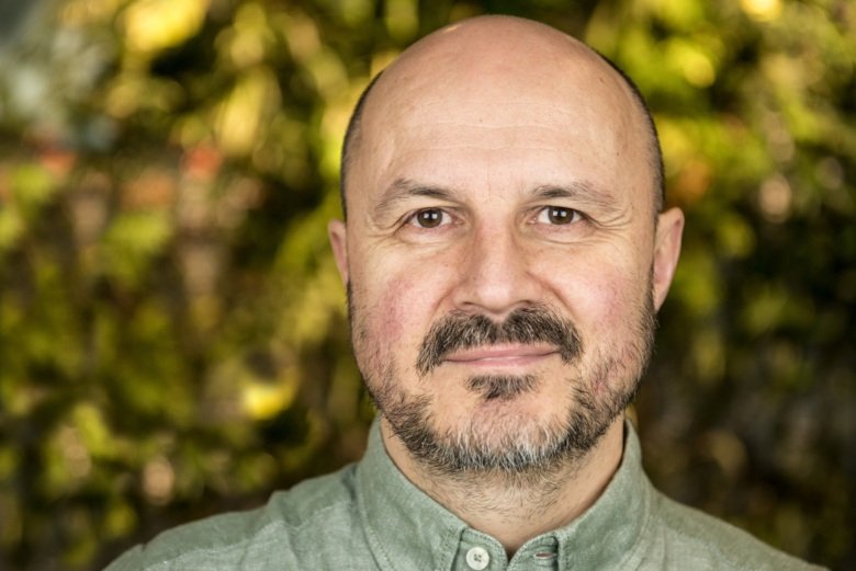 Photo of a man, green leaves in background