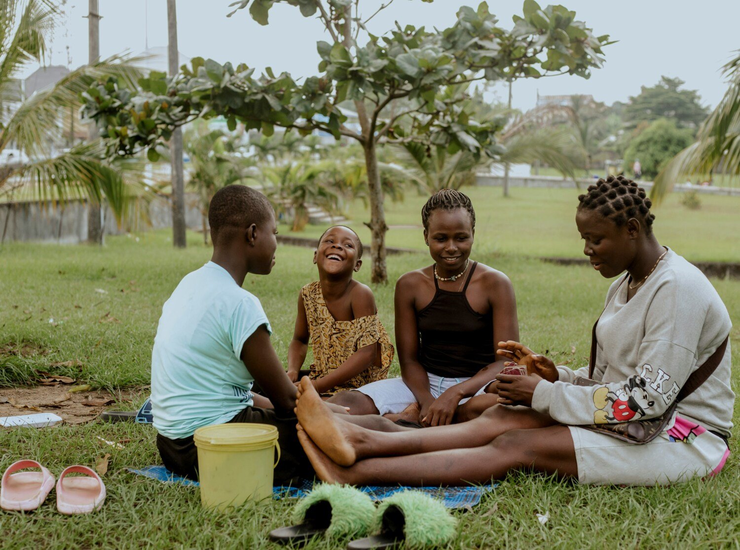 Group of people sitting in the grass and playing card