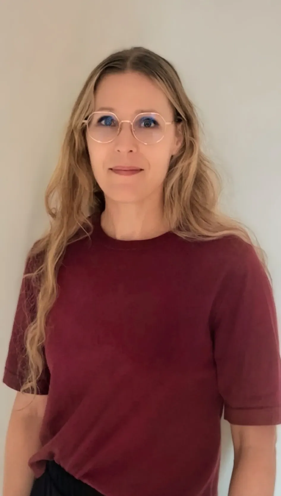 Profile picture of a woman with long blonde hair, glasses and a burgundy top