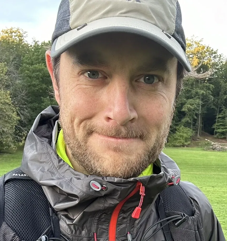 Portrait of a smiling man, wearing a cap, outdoors.