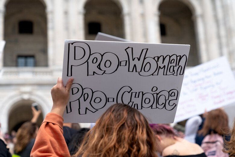 Woman holding a sign with the words "Pro Woman, Pro Choice".