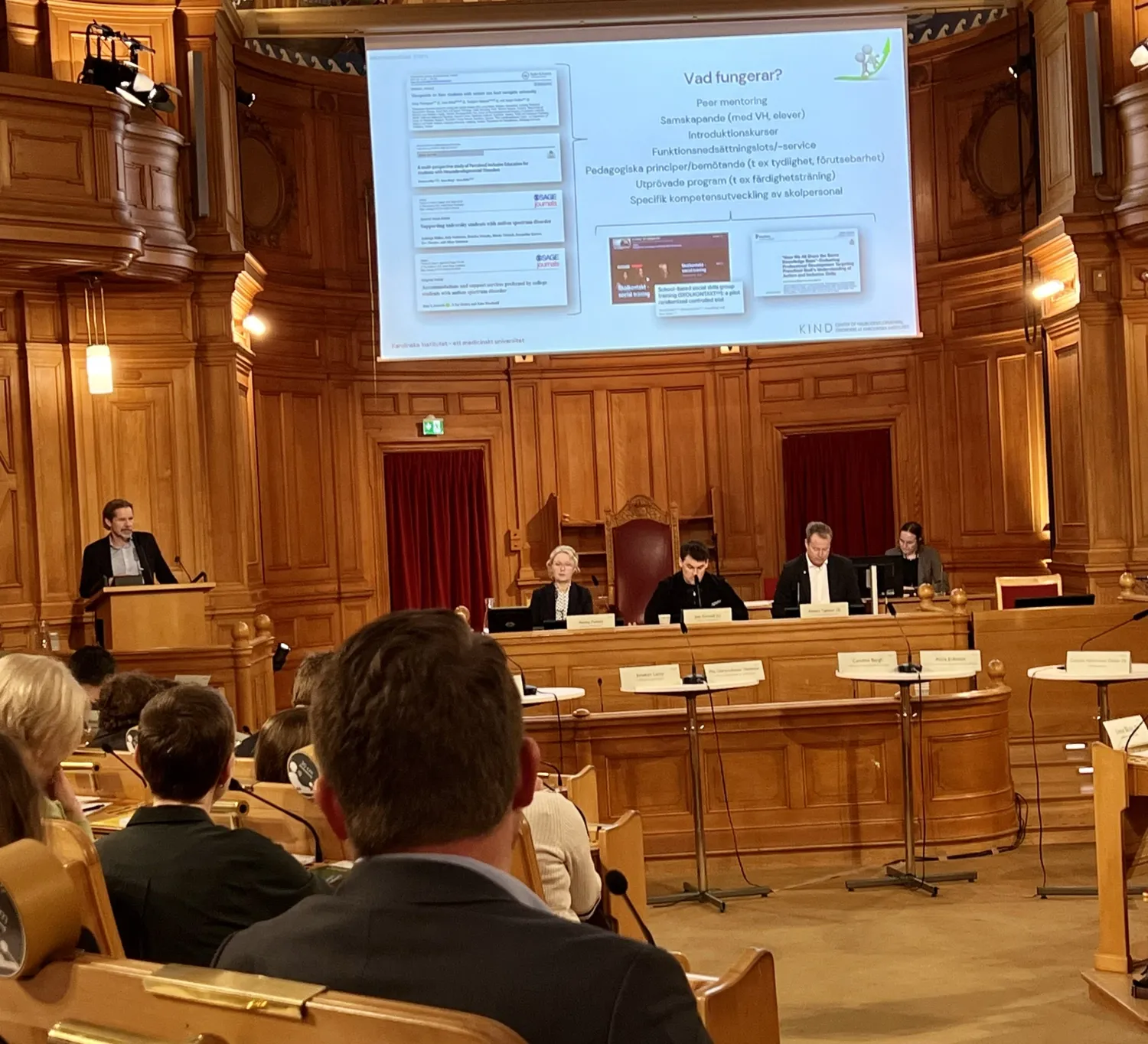 En man vid ett podium samt publik.