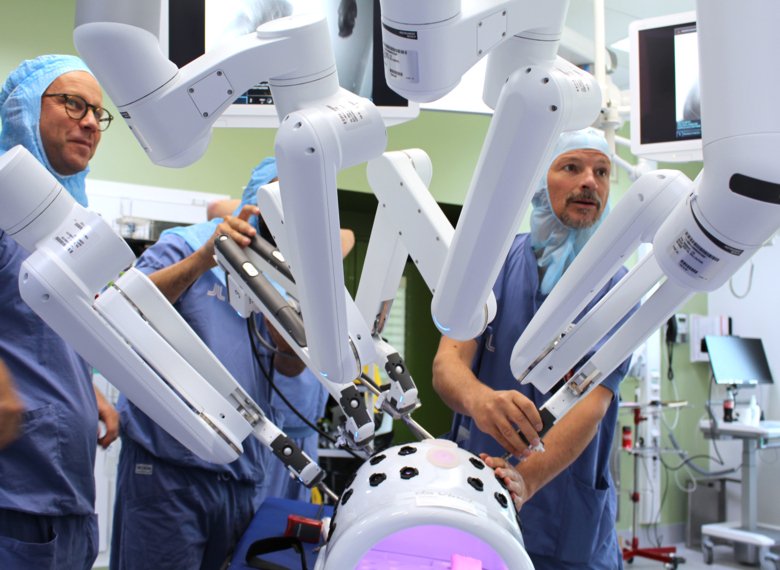 Två operationsklädda kirurger använder avancerad robotkirurgi.
