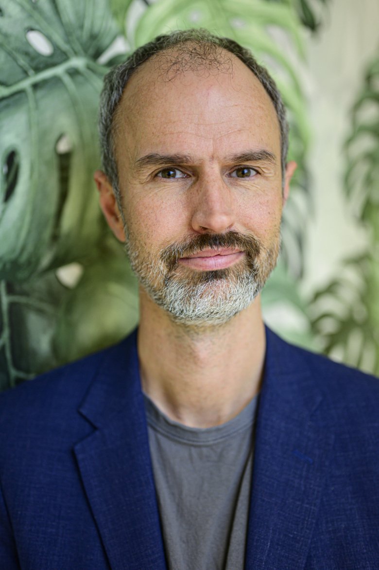 Porträtt av Christian Rück framför grönska.