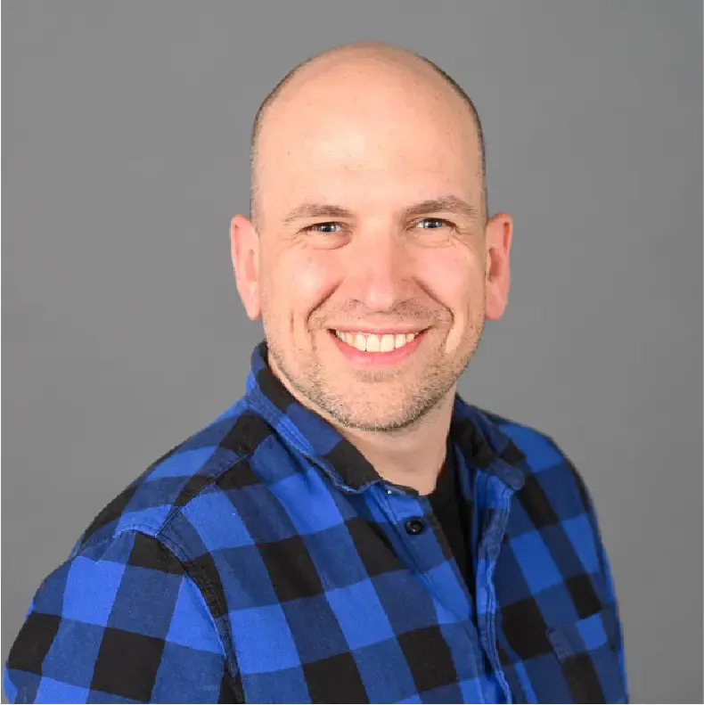Portrait photo of a man wearing a blue plaid shirt.