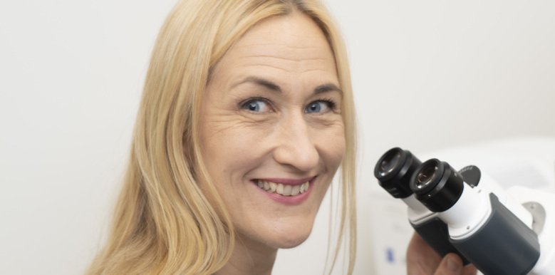 Camilla Svenson in front of a microscope.