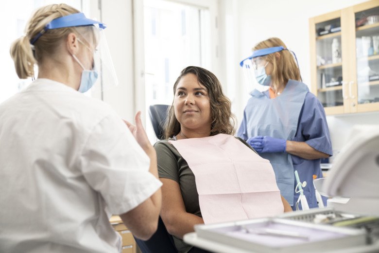 Behandling, patient i stol, tandläkare och tandsköterska.