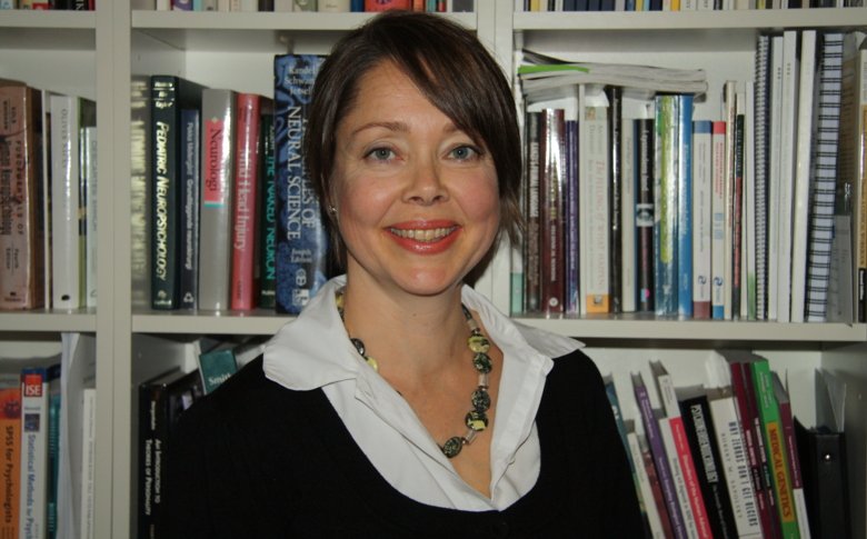 Portrait of Tatja Hirvikoski in front of a book shelf.