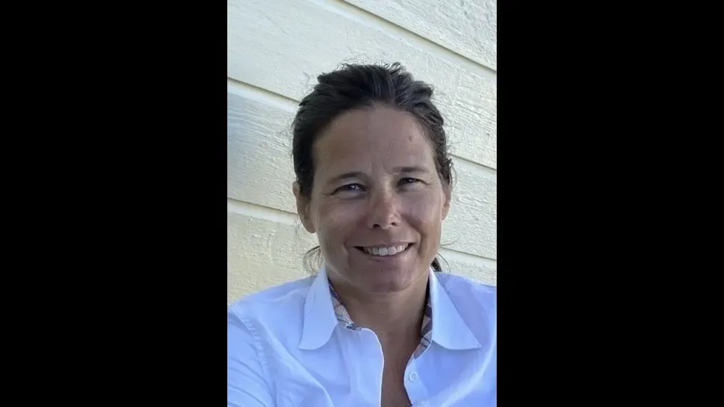 Profile photo of a woman with brown hair wearing a white shirt