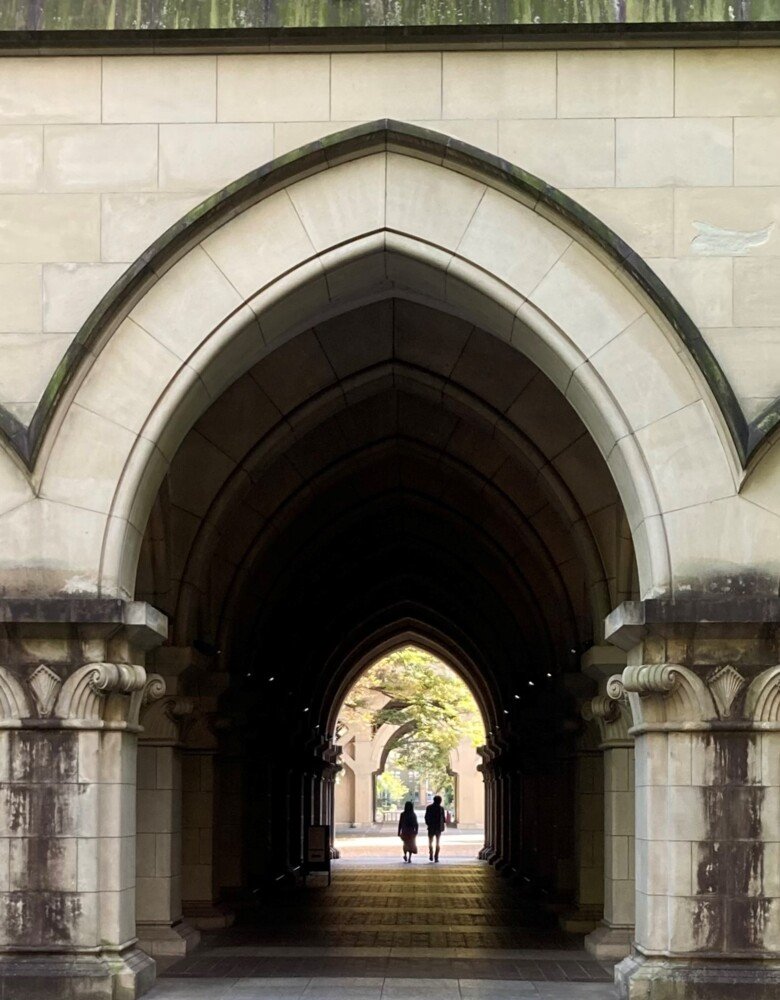 Stone vault in building, two silhouettes are walking through i a distance.