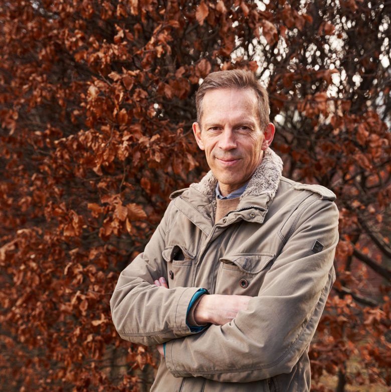 Thomas Perlmann outdoors, in front of a colorful deciduous tree.