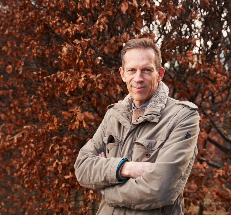 Thomas Perlmann outdoors, in front of a colorful deciduous tree.