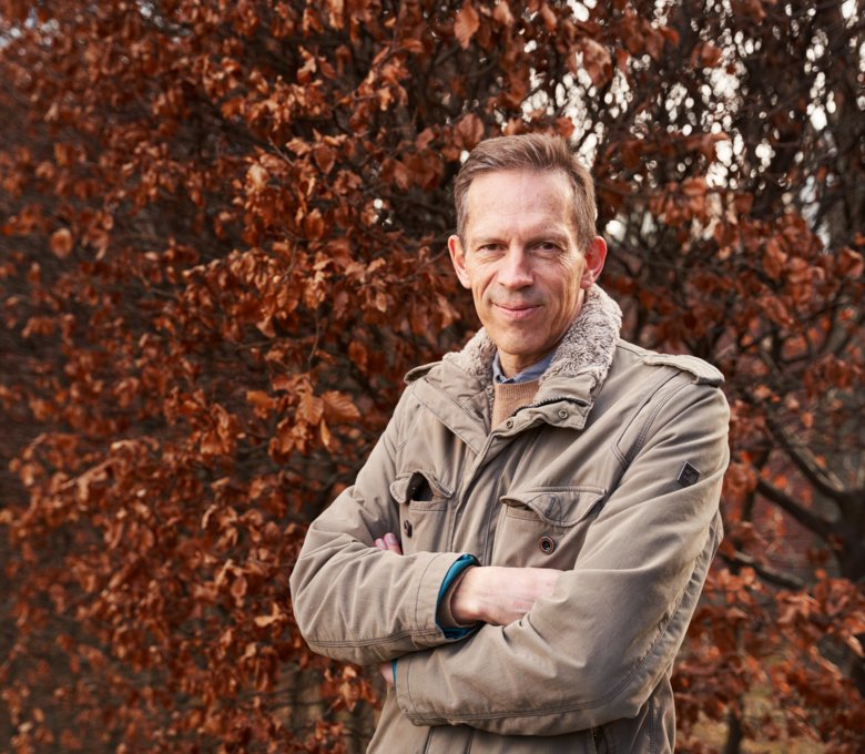 Thomas Perlmann outdoors, in front of a colorful deciduous tree.