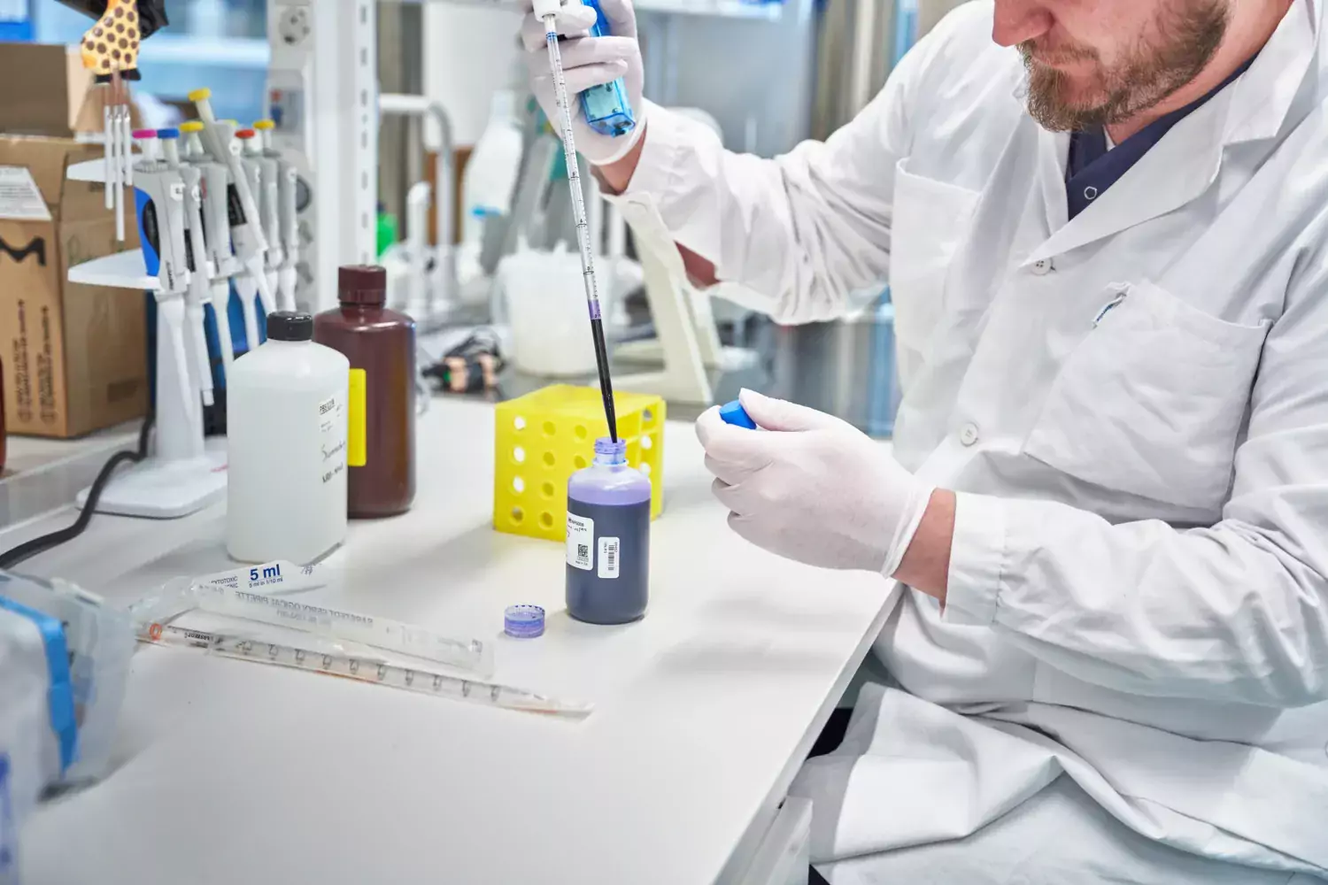 Researcher in lab environment working with a test tube.