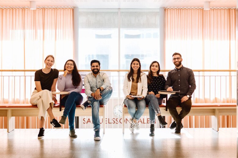 Studenter som sitter på en bänk i Sheele byggnaden på campus Solna.