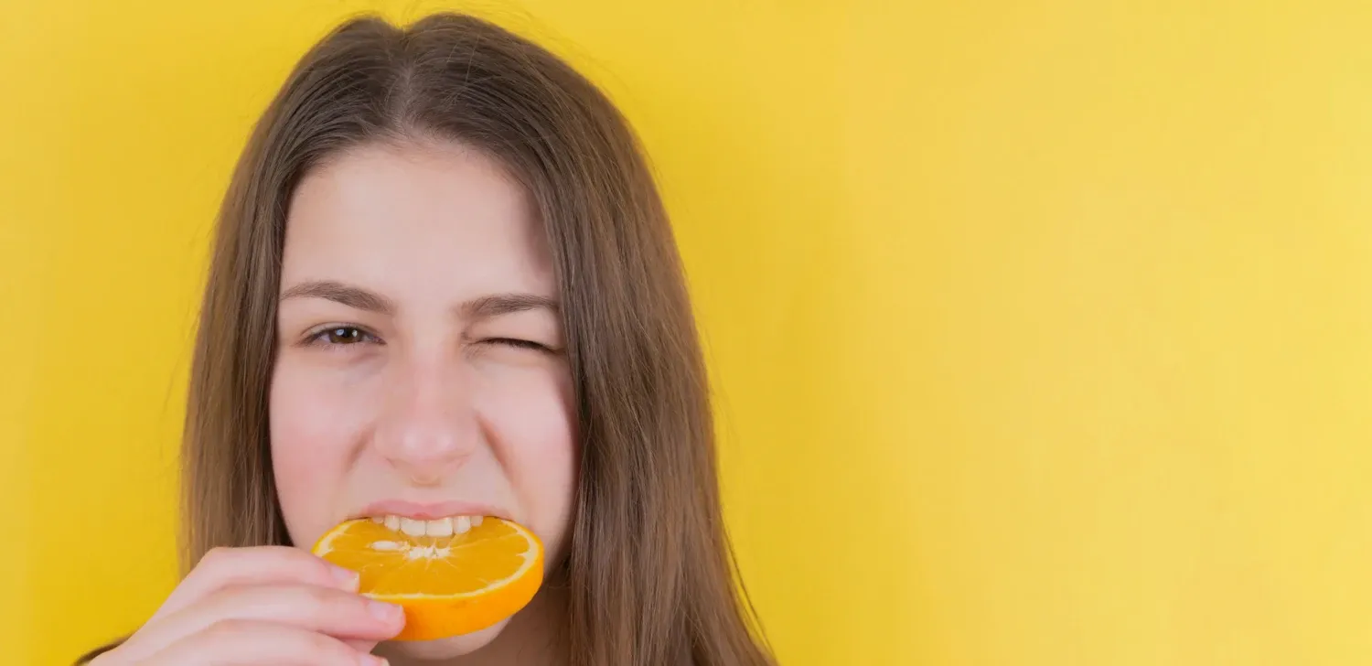 Person tasting an orange