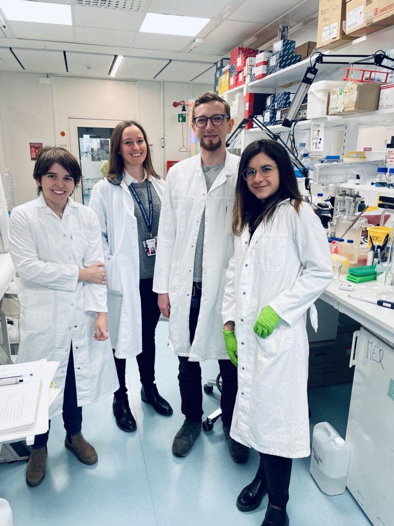 four people in white lab. coats in a lab.