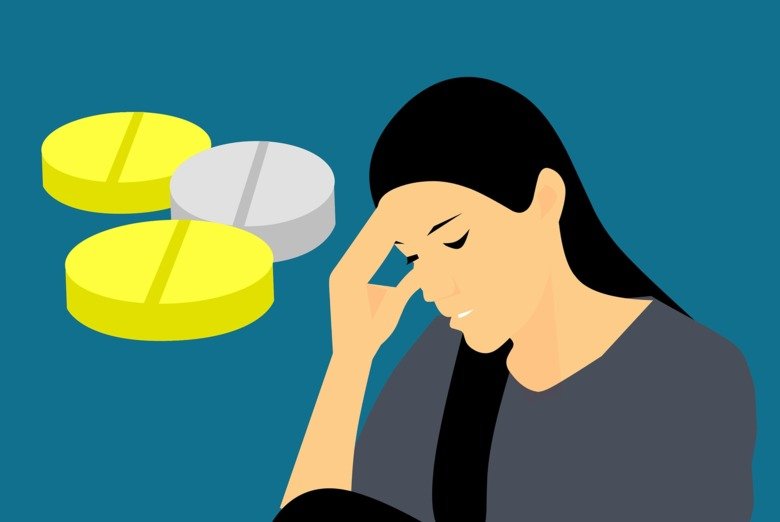 Woman with headache or other disease, pills in the background.