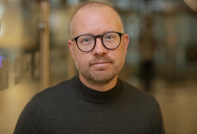 Porträttbild av Johan Åhlen med svarta runda glasögon.