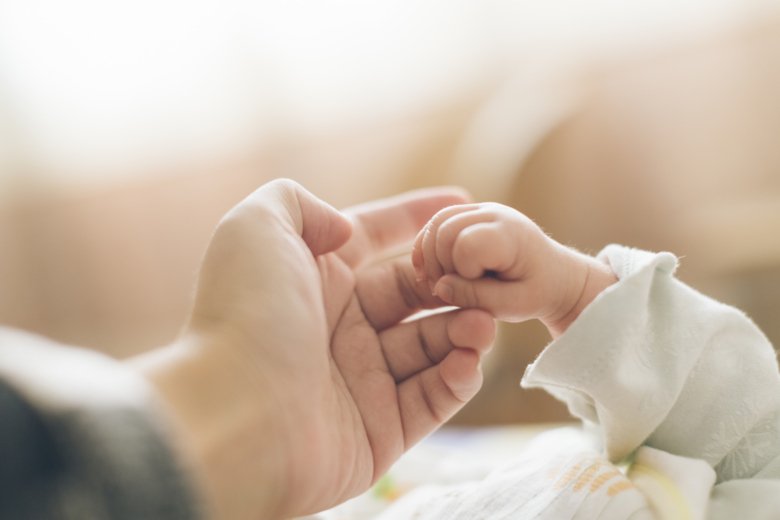 Photo of mother and baby holding hands.