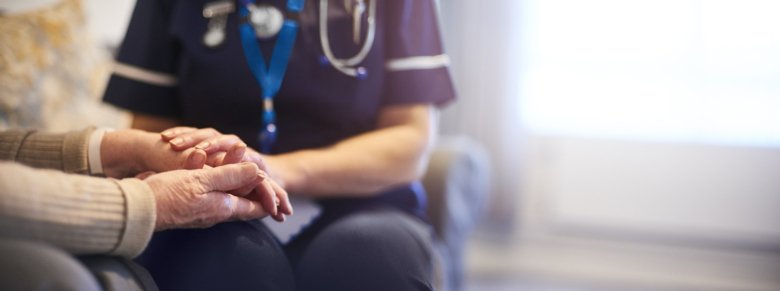 Photo of nurse holding elderly person's hands.