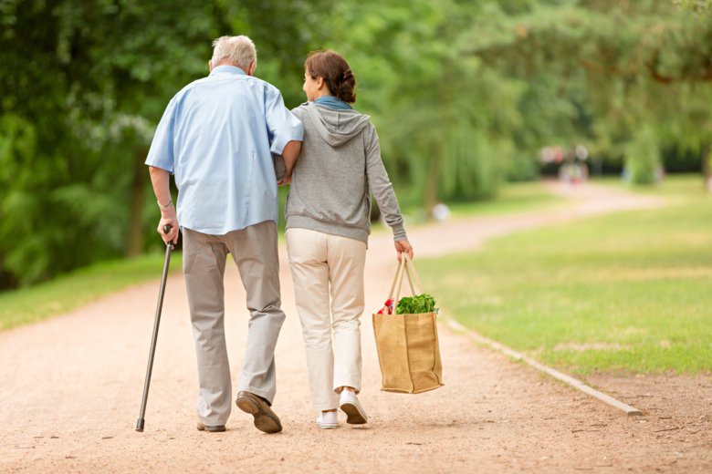 Photo of older man with a cane walking with woman.