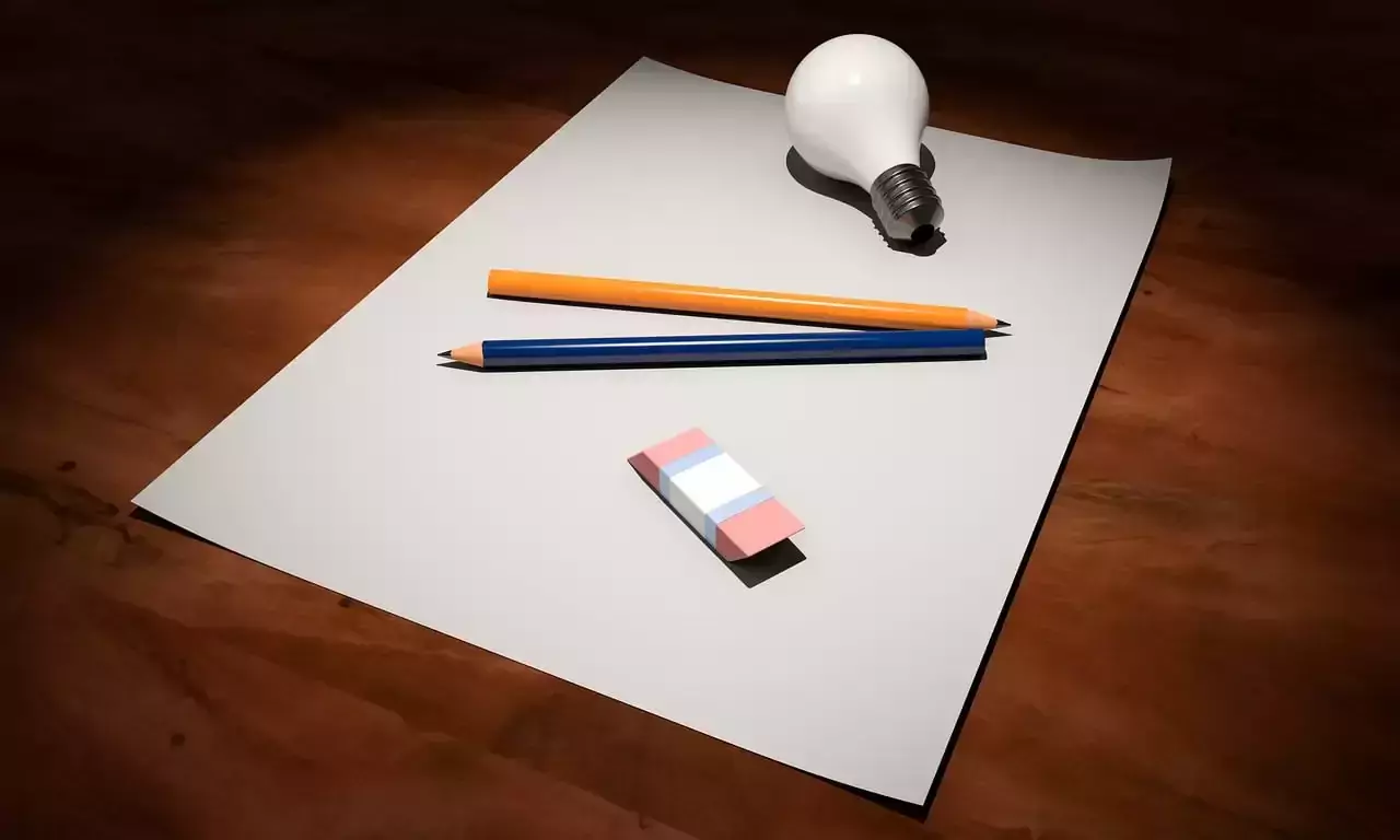 Bild på en blank A4 sida som det ligger två pennor, en sudd och en vit glödlampa på.
