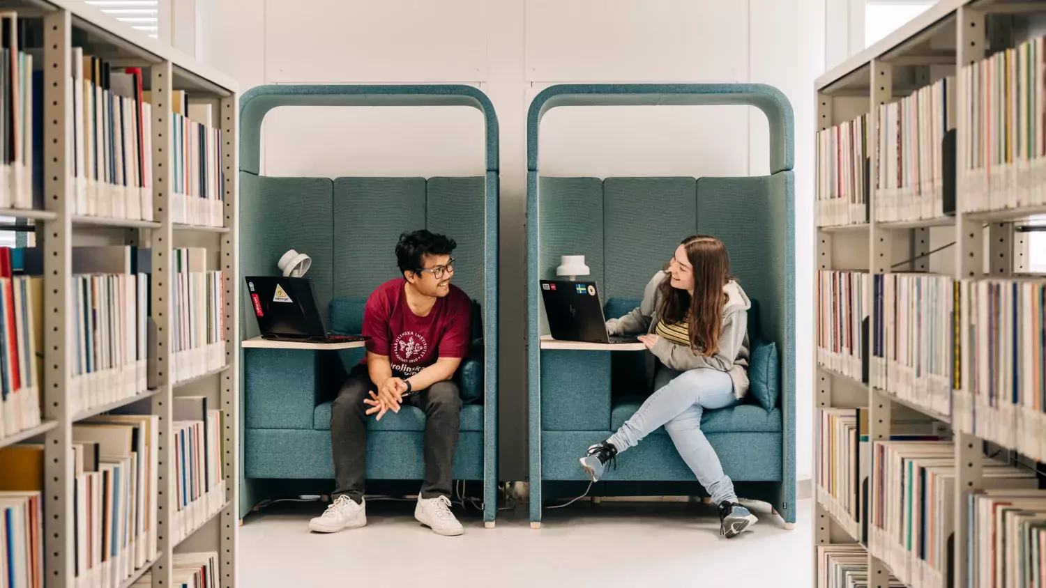 Två studenter sittandes i fåtöljer i universitetsbiblioteket i Solna.