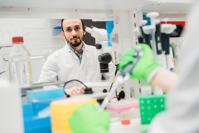 Man in lab operating a microscope.