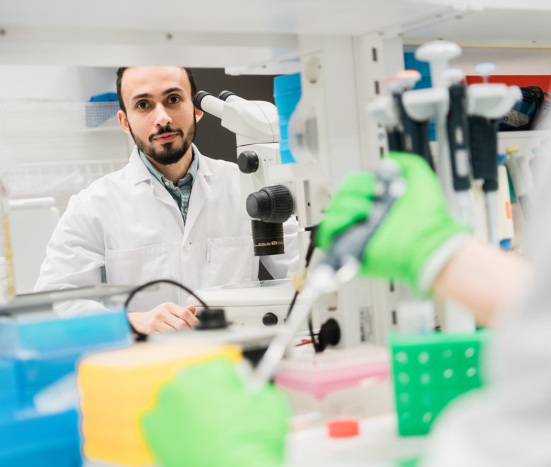 Man in lab operating a microscope.