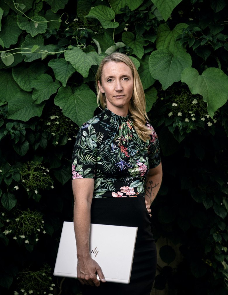 Photo of Marie Holmqvist holding a computer in front of a bush.