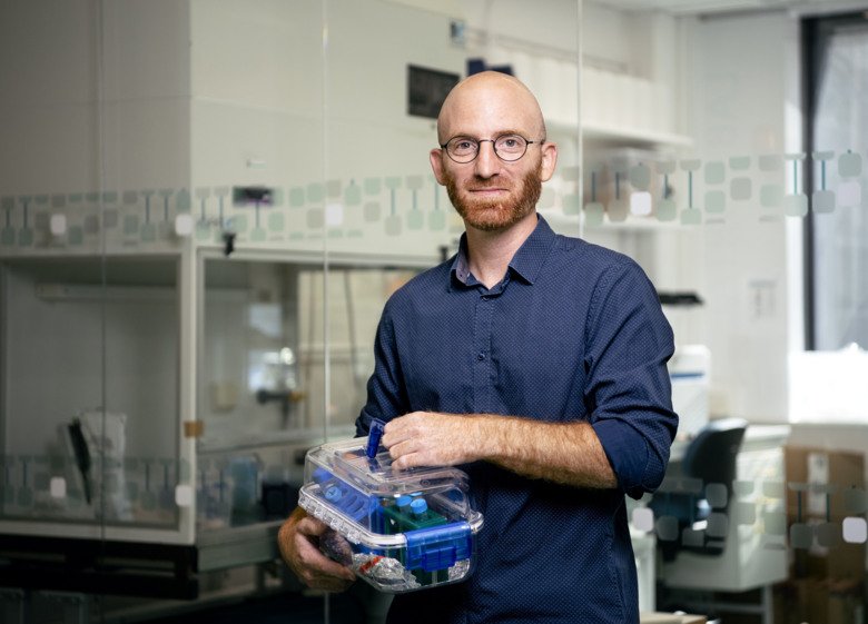 Photo of Martin Cornillet holding a box contaning test tubes.