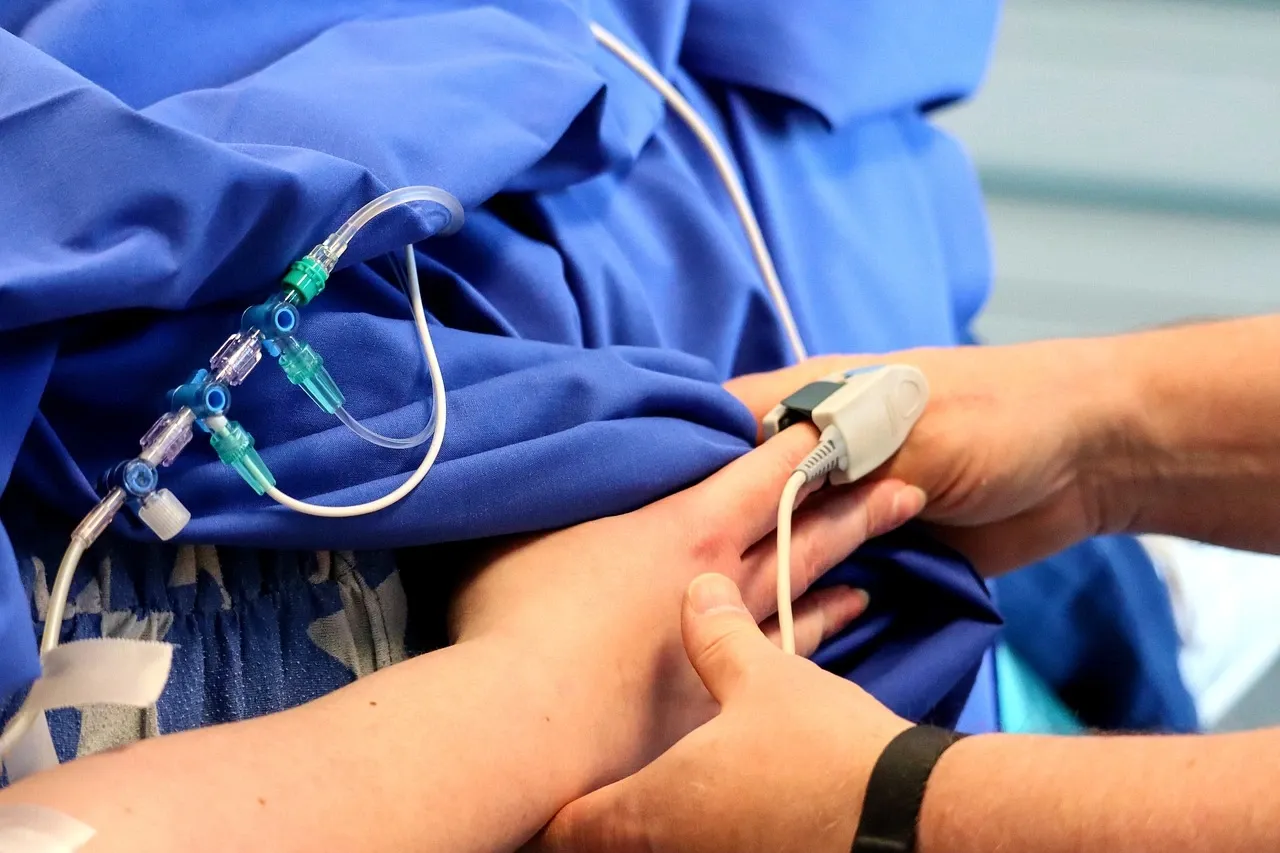 someone lying under a gurney in an operating theatre. only hand visible with cords