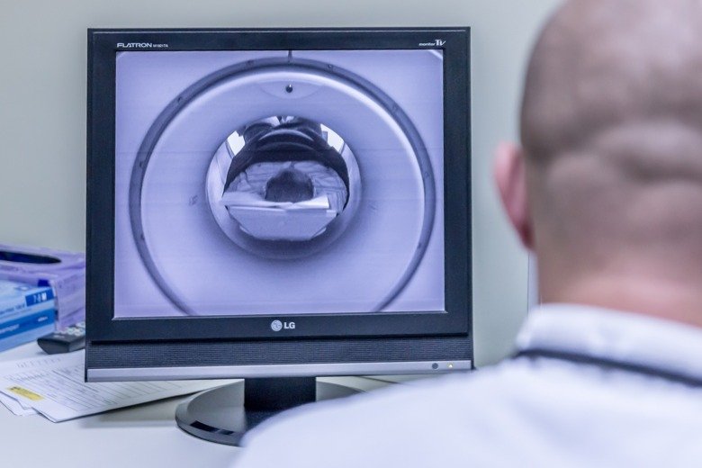 Man viewing a screen showing a person in brain-scan camera