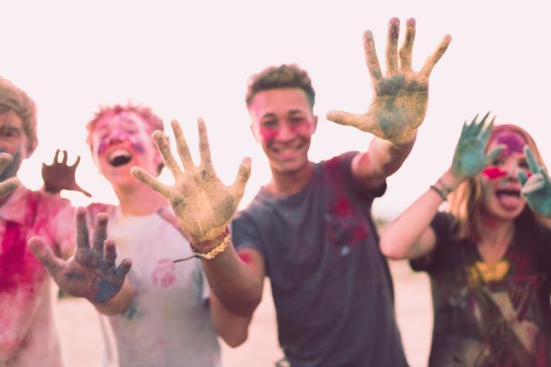Young people smiling holding up their hands with paint on them