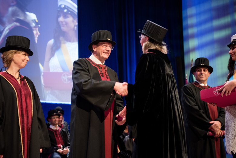 Professors in hats and robes, shaking hands at the inauguration ceremony in Aula Medica 2016.
