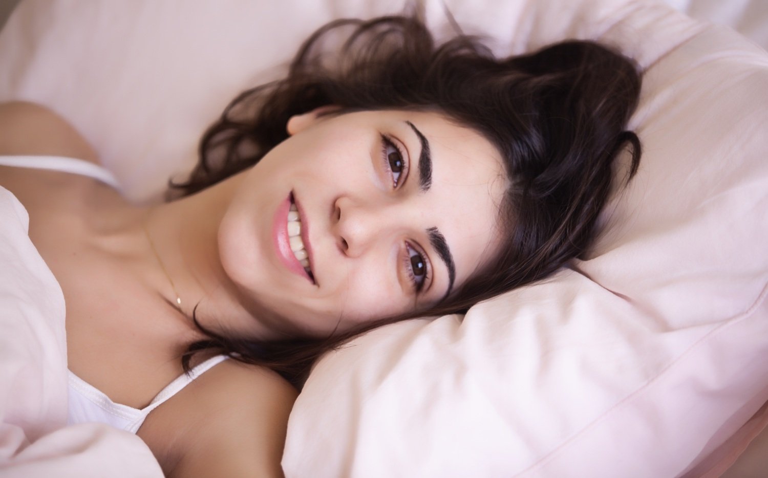 Woman with her head on a pollow, looking fresh and awake.