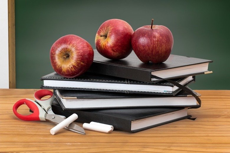 Pile of books and some apples on a desk