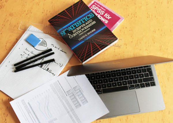 Books on statistics and written sheets on top of each other on a desk