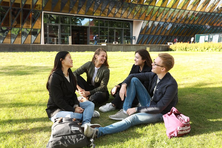 Students smiling and sitting together in the grass.