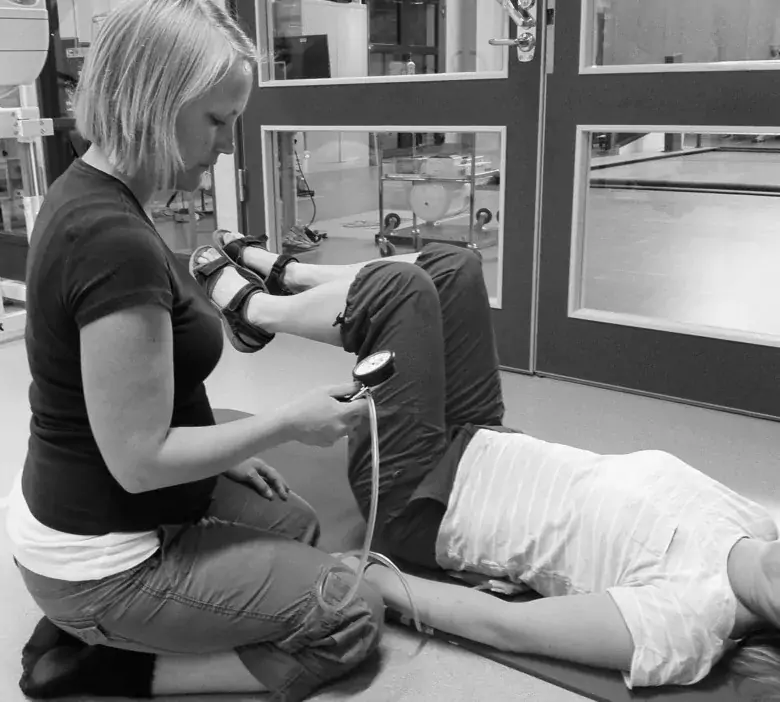 Foto av Testledare Tina Borg som undersöker deltagarens förmåga att använda kroppens alla magmuskellager när ryggen hålls still samtidigt som höftleden rörs.