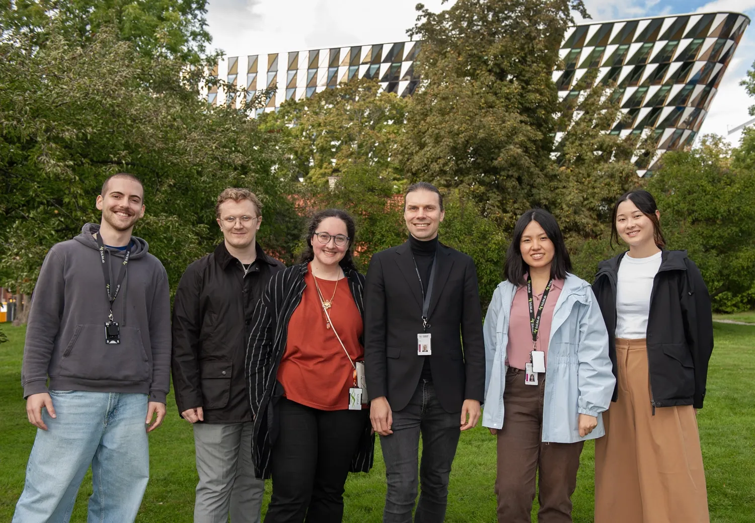 A group of six people standing next to each other outside for a group portrait.