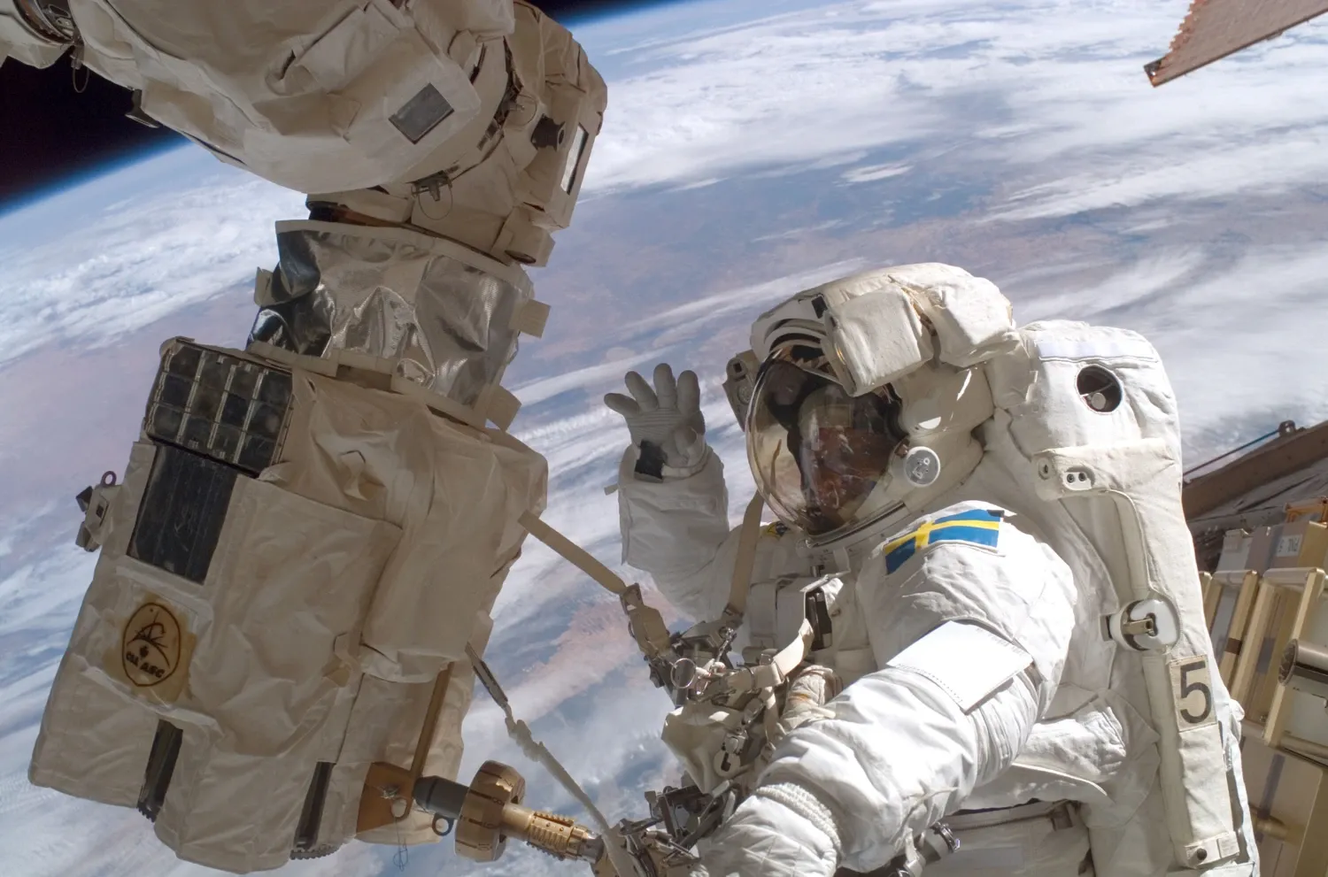 Man in space suit working on equipment on a spacewalk.