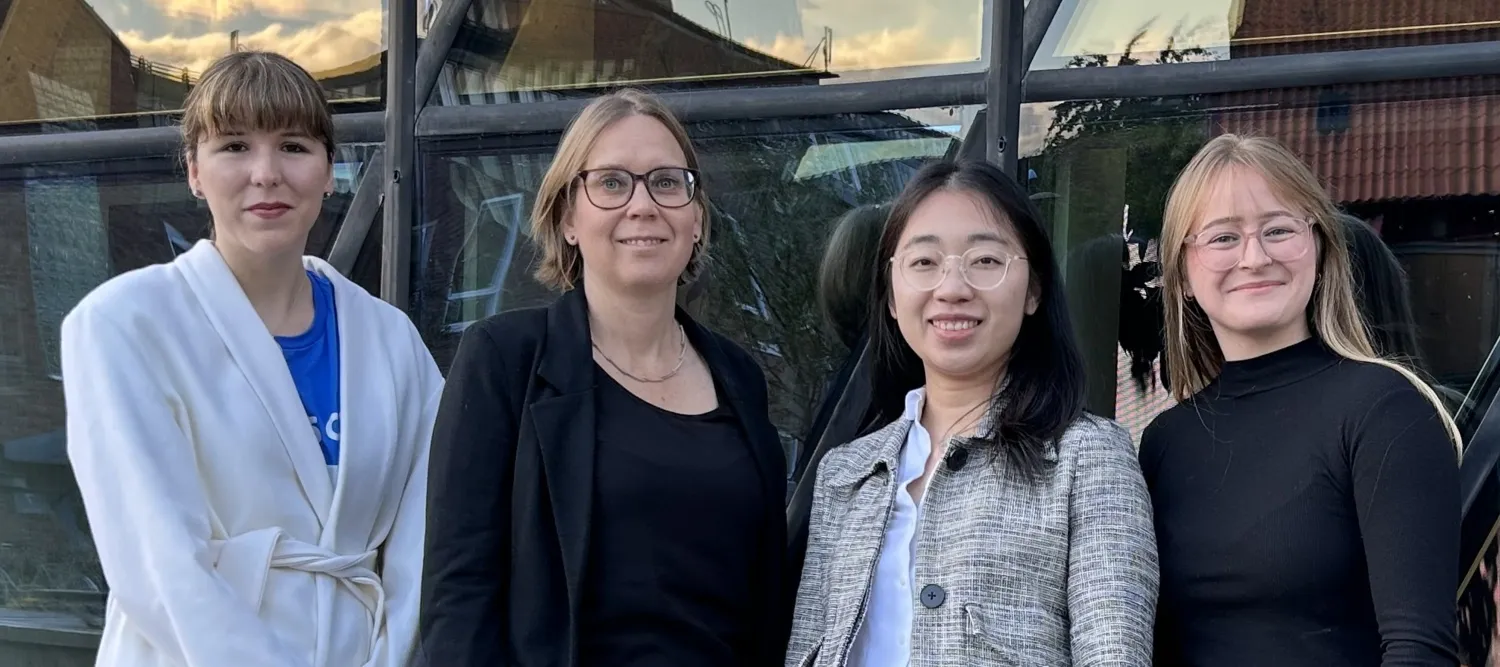 En gruppbild med 4 personer som står utomhus framför en byggnad.