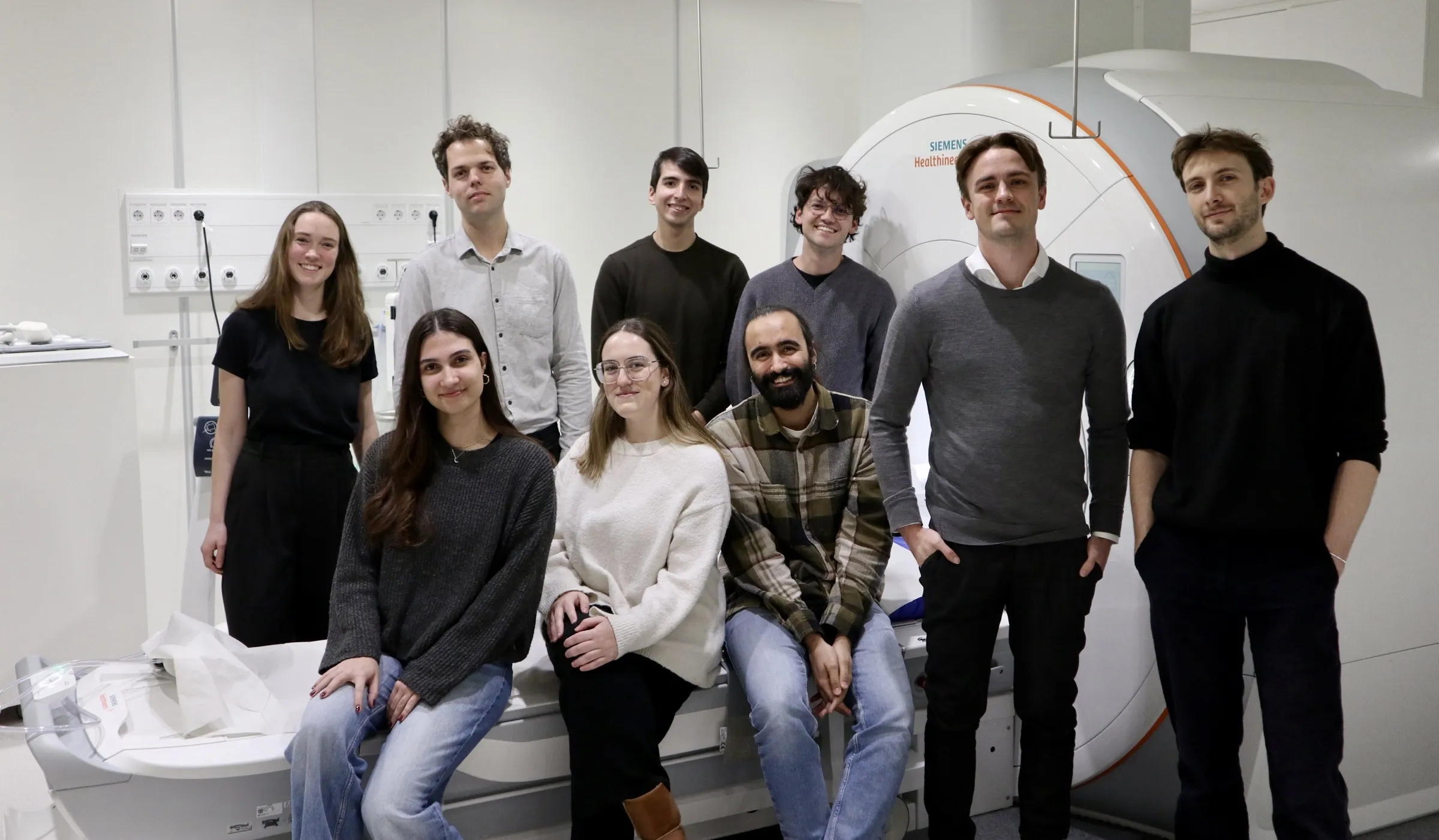 Nine members in front of a MRI scanner