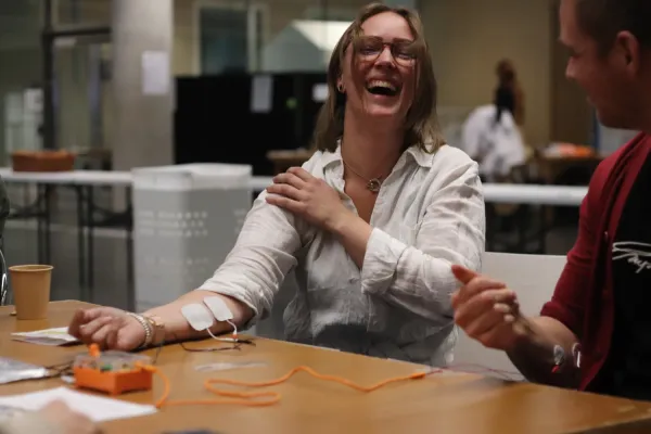 Vilma Alanko with her sleeve rolled up. A fellow visitor controls her arm movements by a neuro-prosthetic.